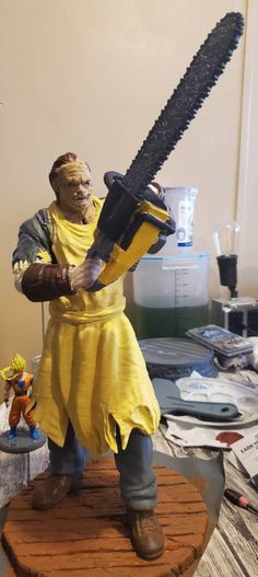 a statue of a man holding a giant chainsaw on top of a wooden table