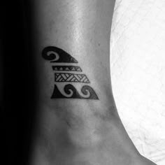 a black and white tattoo on the foot of a woman's leg, with waves coming out of it