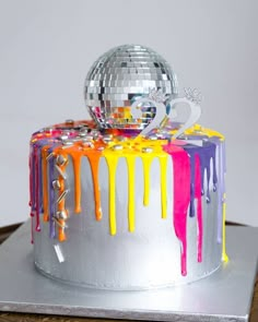 a silver cake with colorful icing and a disco ball on top