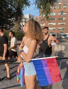 a woman holding a rainbow flag while walking down the street