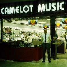 a man standing in front of a camellot music store