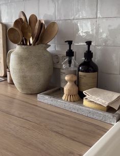 a bathroom counter with wooden utensils, soap and scrubs in a vase