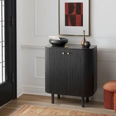 a black cabinet sitting in the corner of a living room next to an orange chair