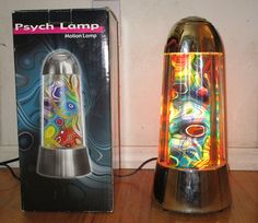 a colorful lamp sitting next to a box on a wooden floor in front of a wall