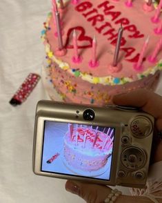 a person holding up a camera to take a picture of a birthday cake with candles on it