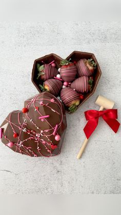 a heart shaped box filled with chocolate covered strawberries next to a small wooden stick