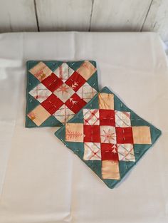 two quilted coasters sitting on top of a white table