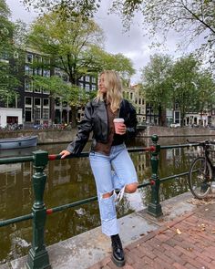 a woman standing on a bridge next to a body of water