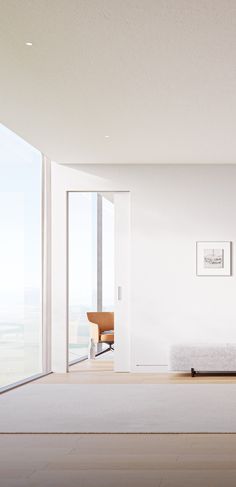 an empty living room with white walls and flooring, looking out onto the ocean