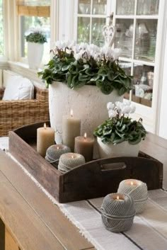 a tray with candles and flowers on top of a table in front of a window