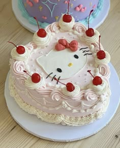 a hello kitty cake with cherries on the top and one has a pink bow