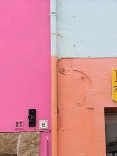 a pink and blue building with a street sign on it