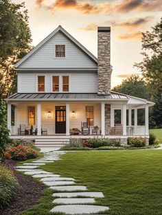 a white house with steps leading up to the front door and covered porch, surrounded by lush green grass