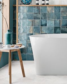 a white bath tub sitting next to a wooden shelf