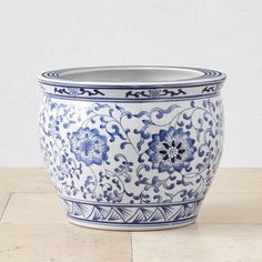 a large blue and white bowl sitting on top of a wooden table next to a wall