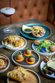 a table topped with plates filled with different types of food next to glasses of wine