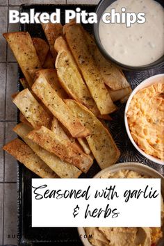 baked pita chips with garlic and ketchup on a black tray next to dip