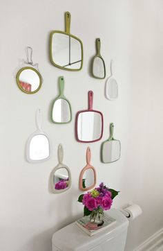 a white toilet sitting in a bathroom next to a wall with mirrors and flowers on it