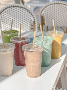 four different colored drinks sitting on top of a table next to each other with straws sticking out of them