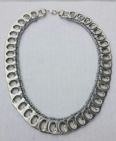 a silver necklace is displayed on a white surface