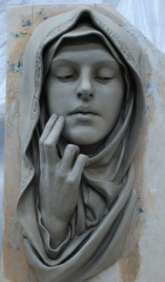 a clay sculpture of a woman with her eyes closed and hands clasped to her face