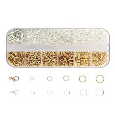 an assortment of gold, silver and white beads in a plastic container with two pairs of rings