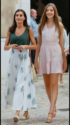 two women walking down the street in dresses