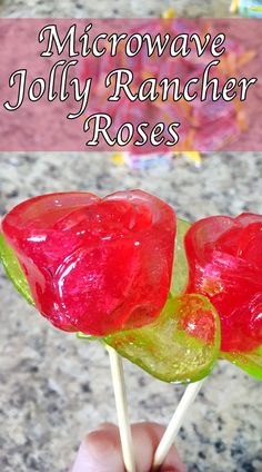 a hand holding two lollipops with the words microwave jolly rancher roses