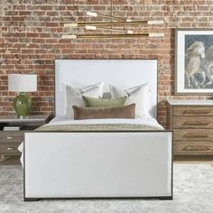 a bedroom with brick walls and white bedding in front of a painting on the wall