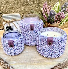 three crocheted candles sitting next to each other on a piece of wood with flowers in the background