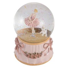 a snow globe with a ballerina in it and a dog on the ground next to it