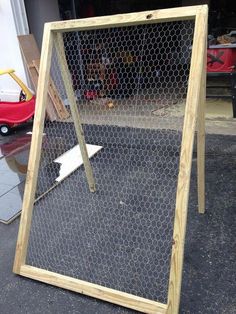 a chicken wire fence sitting on the ground next to a red toy car in front of it