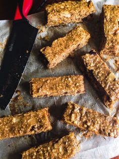 some granola bars are sitting on a piece of parchment paper next to a knife