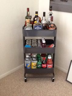 a shelf filled with bottles and drinks on top of a carpeted floor next to a mirror