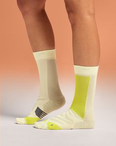 the legs and feet of a person wearing socks with yellow stripes on them, standing in front of a pink background