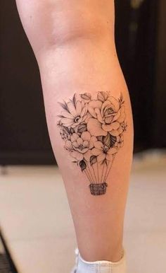 a woman's leg with flowers on it and an air balloon in the middle