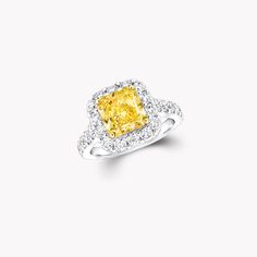 a yellow and white diamond ring with diamonds around it's sidestone, set in 18k white gold