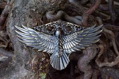 a silver bird brooch sitting on top of a tree