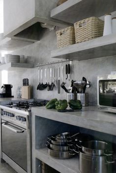 a kitchen with pots and pans on the stove top, shelves holding utensils