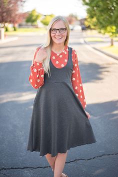 a woman standing in the middle of a street wearing a red and white polka dot shirt dress