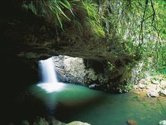 there is a small waterfall in the middle of this cave with green water flowing from it