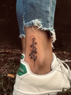 a woman's foot with a small flower tattoo on the left side of her ankle