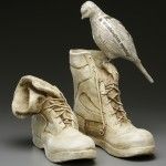 a bird sitting on top of a pair of boots that have been made out of clay