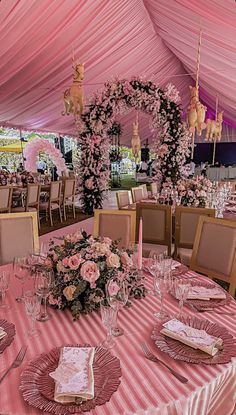 a table set up for a formal function with pink flowers and napkins on it