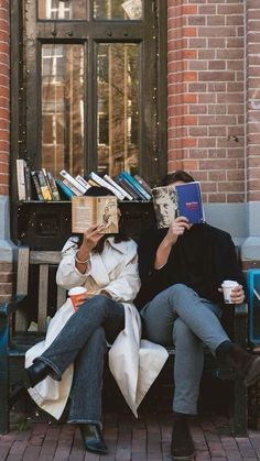 two people sitting on a bench with books in their hands and one person holding a book