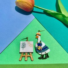 a pair of earrings sitting on top of a table next to a tulip