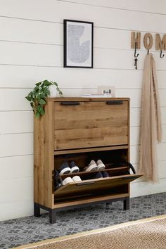 a wooden shoe rack with two pairs of shoes on it in front of a white wall