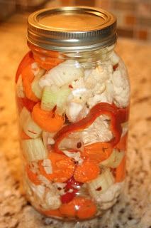 a mason jar filled with carrots, cauliflower and onions sitting on a counter