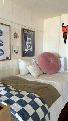 there is a bed with pillows and pictures on the wall