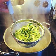 someone is cooking zucchini in a pot on the stove